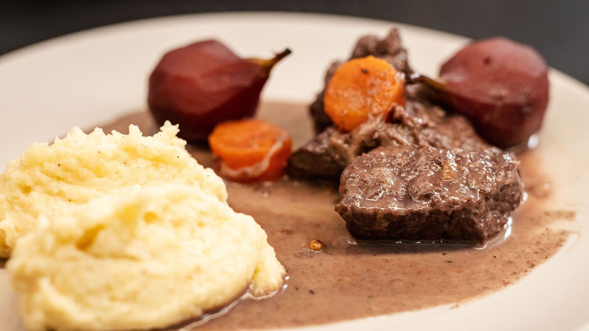 Civet de biche mijoté au vin rouge avec gelée de groseilles, gratin dauphinois et champignons poêlés.